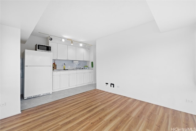 kitchen with sink, light hardwood / wood-style floors, white cabinets, decorative backsplash, and white refrigerator