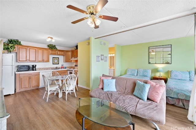 living room featuring light hardwood / wood-style flooring, a textured ceiling, and ceiling fan