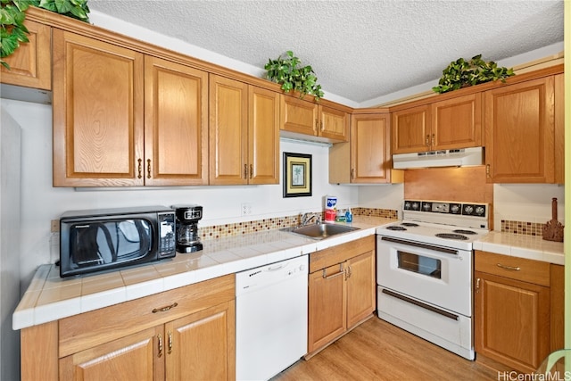 kitchen with white appliances, tile countertops, a textured ceiling, and sink