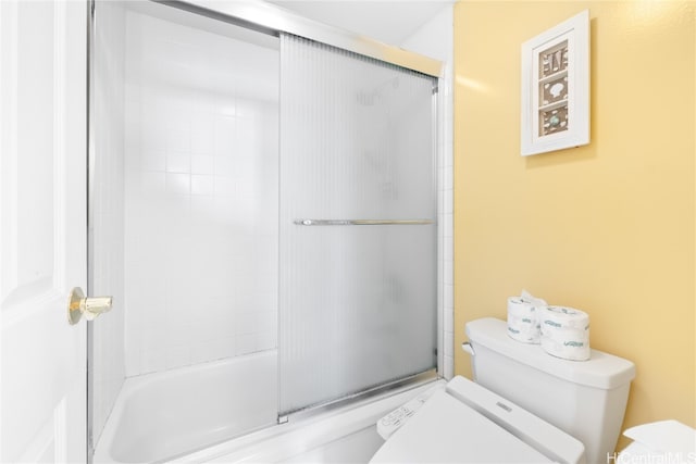 bathroom featuring toilet and bath / shower combo with glass door