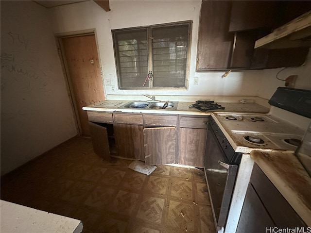 kitchen with sink, dark brown cabinets, and white range oven