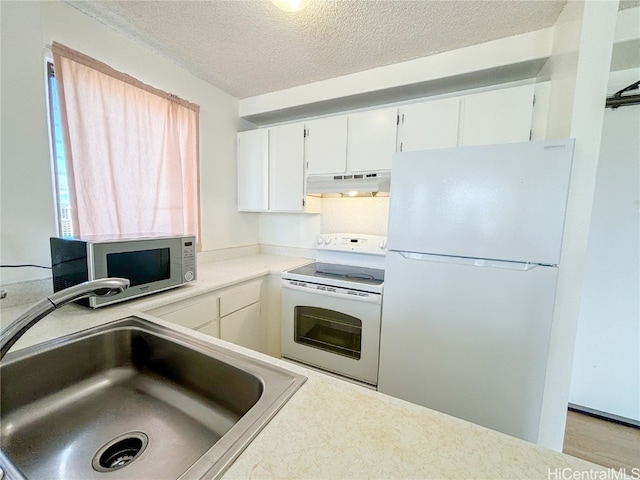 kitchen with white appliances, white cabinets, a textured ceiling, and sink