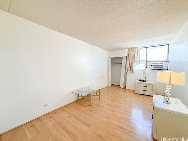 unfurnished bedroom featuring cooling unit, a textured ceiling, and light hardwood / wood-style flooring