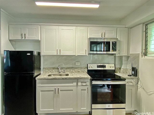 kitchen with stainless steel appliances, sink, white cabinets, light stone counters, and tasteful backsplash