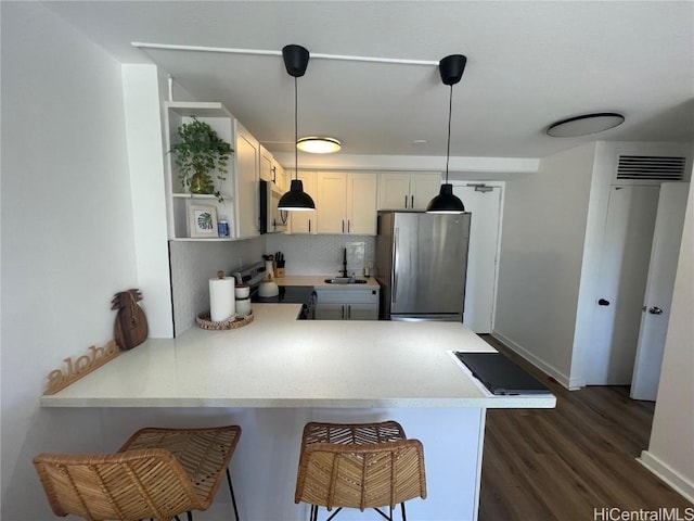 kitchen featuring a breakfast bar, decorative light fixtures, dark hardwood / wood-style flooring, kitchen peninsula, and stainless steel appliances