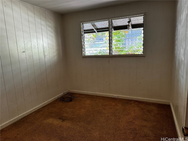 carpeted empty room featuring wooden walls