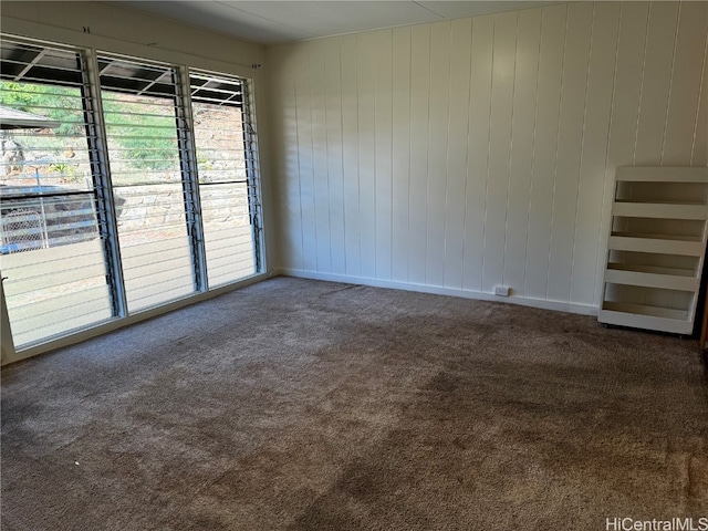 empty room with wood walls and carpet floors