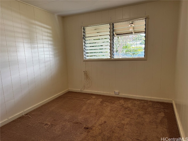 unfurnished room with wooden walls and dark carpet