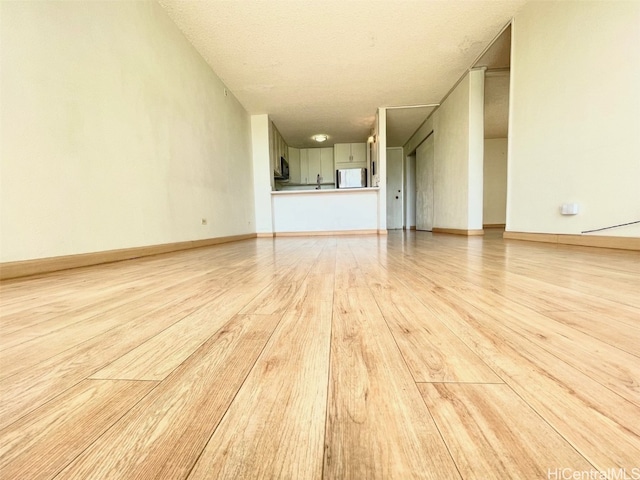 unfurnished living room with a textured ceiling and light hardwood / wood-style floors