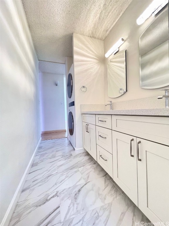 laundry area featuring a textured ceiling, sink, and stacked washer / dryer