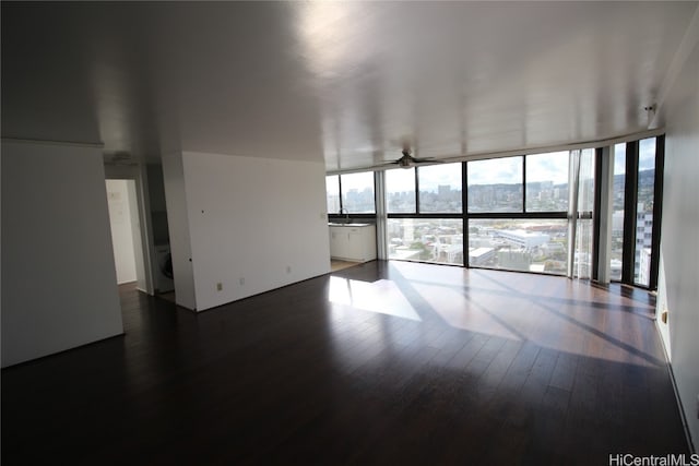 unfurnished living room featuring a wall of windows, ceiling fan, sink, and dark hardwood / wood-style flooring