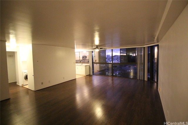 unfurnished living room with washer / clothes dryer, sink, dark wood-type flooring, and ceiling fan