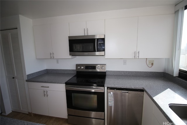 kitchen with dark wood-type flooring, stainless steel appliances, and white cabinets