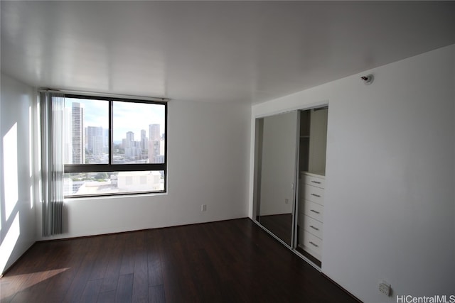 unfurnished bedroom featuring a closet and dark hardwood / wood-style floors