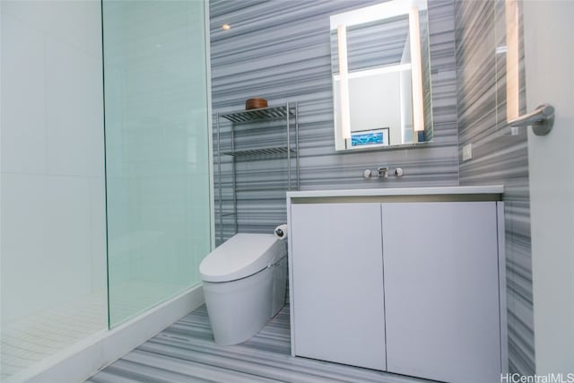 bathroom featuring vanity, toilet, tile walls, and walk in shower