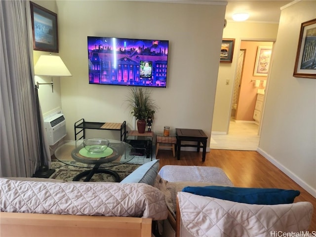 living room featuring an AC wall unit, ornamental molding, and hardwood / wood-style floors