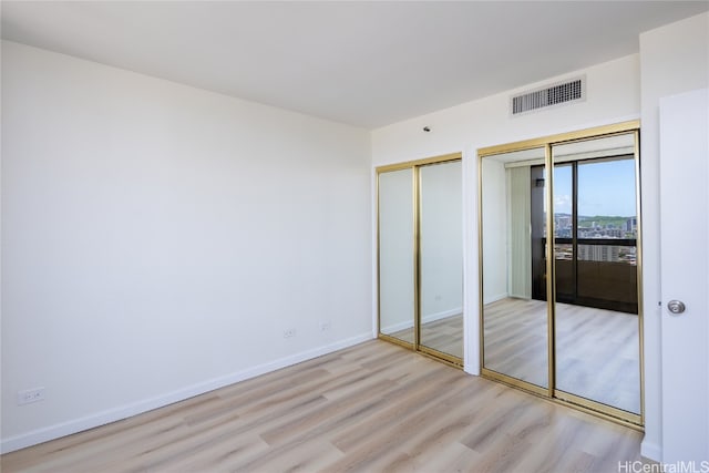 unfurnished bedroom featuring light hardwood / wood-style floors and two closets