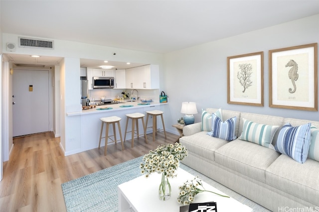 living room with sink and light hardwood / wood-style flooring