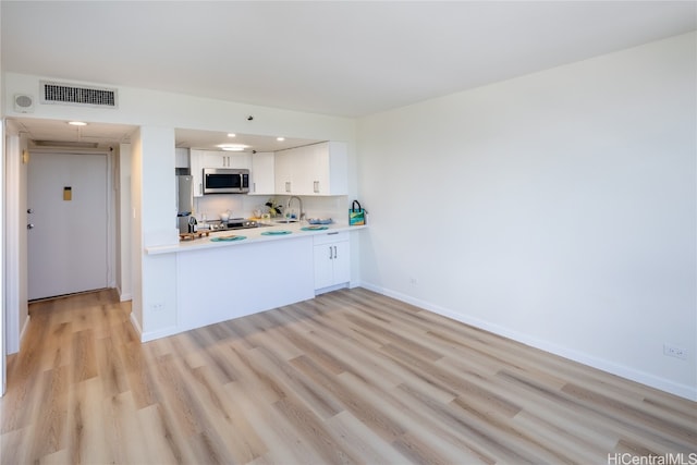 kitchen featuring sink, appliances with stainless steel finishes, white cabinets, and light hardwood / wood-style floors