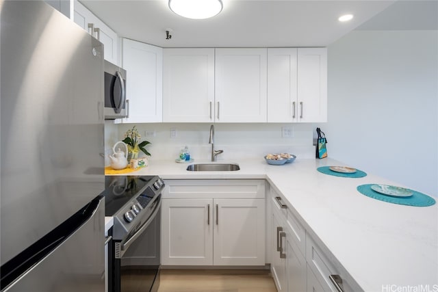 kitchen featuring appliances with stainless steel finishes, white cabinetry, sink, and light hardwood / wood-style floors