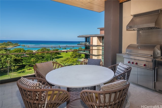 balcony with exterior kitchen, area for grilling, and a water view