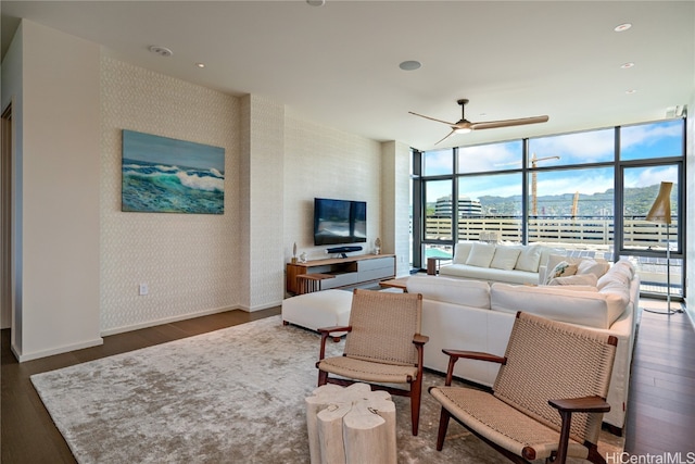 living room with a wall of windows, dark wood-type flooring, and ceiling fan