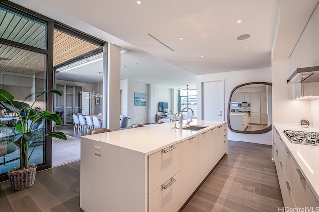 kitchen featuring white cabinets, hardwood / wood-style floors, a kitchen island with sink, stainless steel gas cooktop, and sink