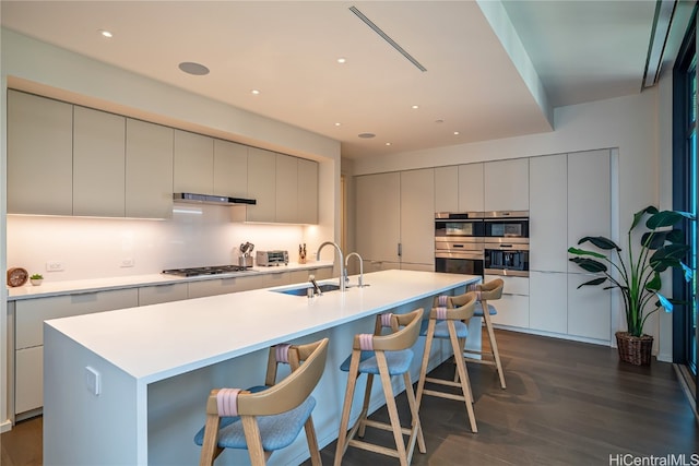 kitchen with a spacious island, appliances with stainless steel finishes, sink, and dark wood-type flooring