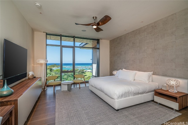 bedroom with dark wood-type flooring, ceiling fan, a water view, and floor to ceiling windows