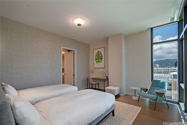 bedroom with a wall of windows, a mountain view, and hardwood / wood-style flooring