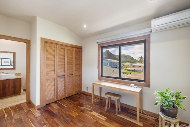 interior space with dark wood-type flooring, a closet, vaulted ceiling, and a wall unit AC