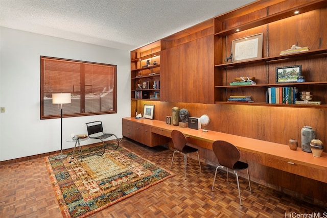 office area featuring built in desk, built in features, dark parquet floors, and a textured ceiling