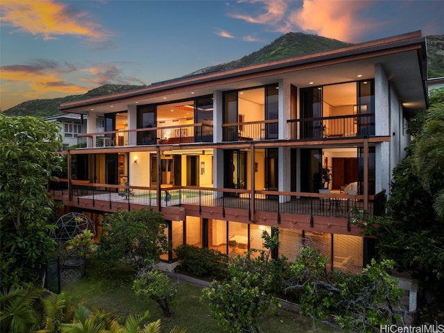 back house at dusk featuring a balcony