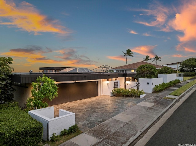 3869 Pokapahu Pl, Honolulu, HI 96816 - contemporary home featuring an attached garage, decorative driveway, solar panels, fence, and stucco siding