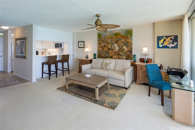 carpeted living room featuring ceiling fan and a textured ceiling