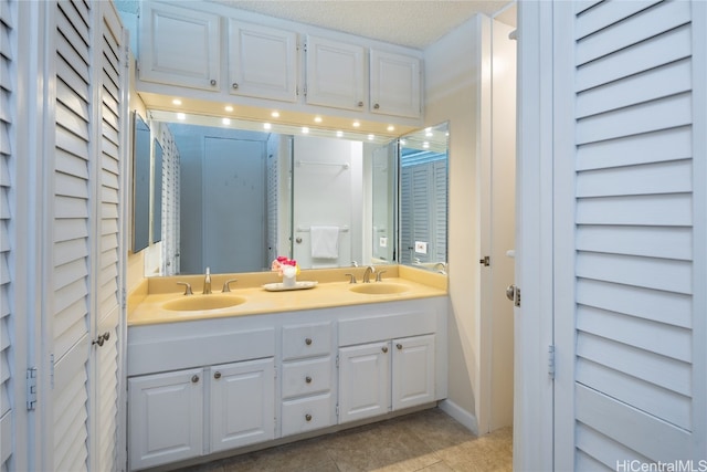 bathroom with vanity, a textured ceiling, and tile patterned flooring