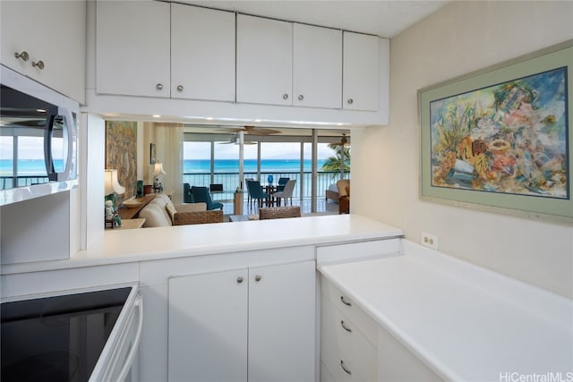 kitchen with white cabinetry, a water view, and range