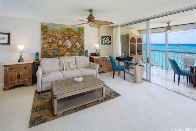 carpeted living room featuring a textured ceiling, a water view, and ceiling fan