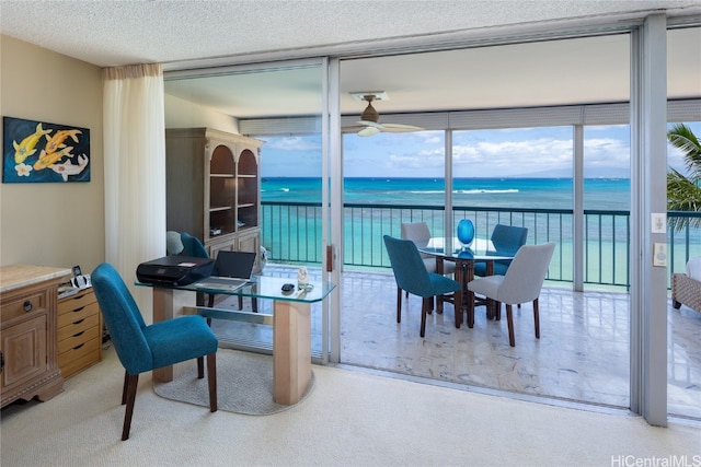 carpeted dining space with floor to ceiling windows, a textured ceiling, a water view, and ceiling fan