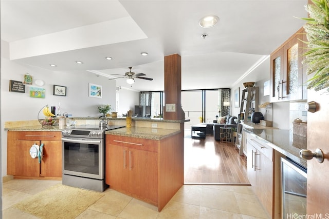 kitchen featuring stone counters, stainless steel range with electric stovetop, light hardwood / wood-style floors, and beverage cooler