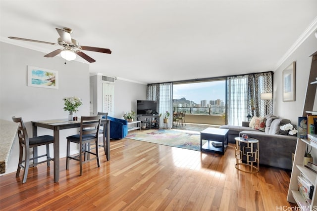 living room with ornamental molding, expansive windows, wood-type flooring, and ceiling fan