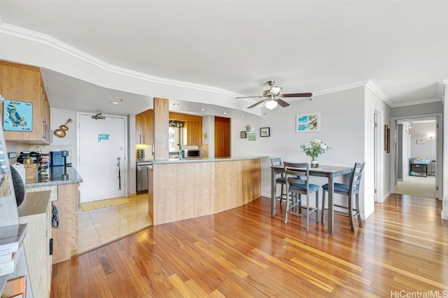 kitchen with ornamental molding, kitchen peninsula, light hardwood / wood-style floors, and ceiling fan