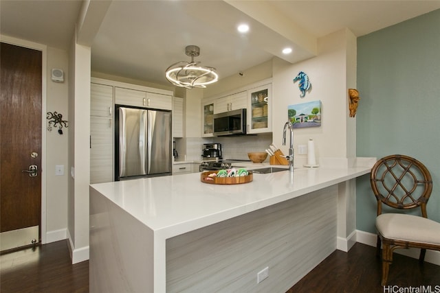 kitchen featuring kitchen peninsula, white cabinetry, stainless steel appliances, and dark hardwood / wood-style flooring