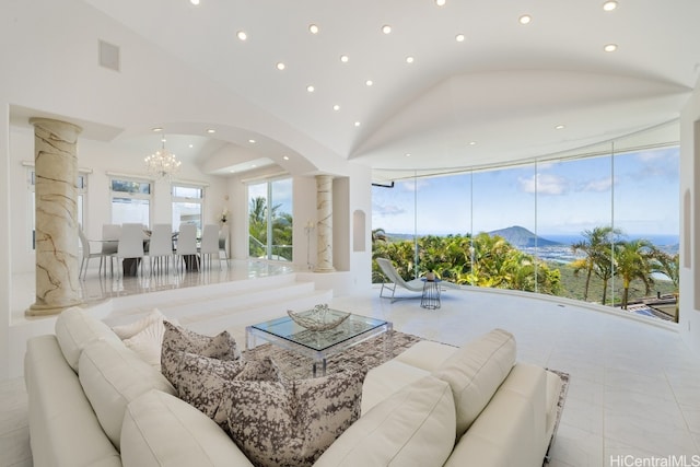 living room with light tile patterned floors, high vaulted ceiling, ornate columns, a notable chandelier, and a mountain view