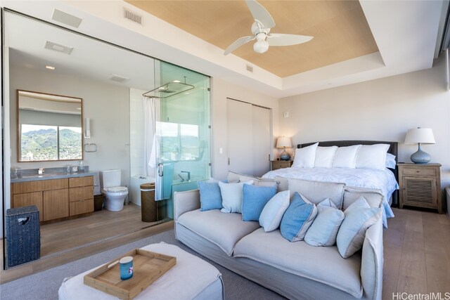 bedroom with a closet, ceiling fan, a raised ceiling, and hardwood / wood-style floors