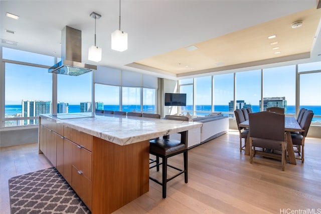 kitchen featuring island range hood, a large island, a water view, and light hardwood / wood-style floors