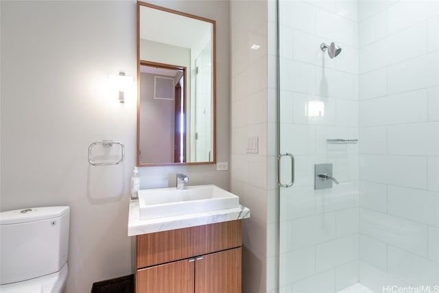 bathroom with vanity, a shower with shower door, and toilet