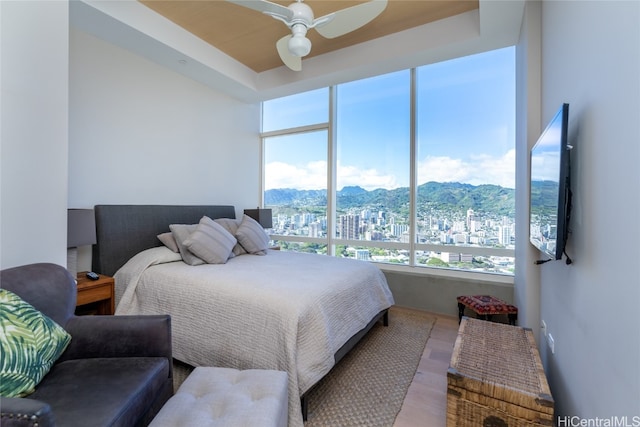 bedroom featuring ceiling fan, wood-type flooring, and multiple windows