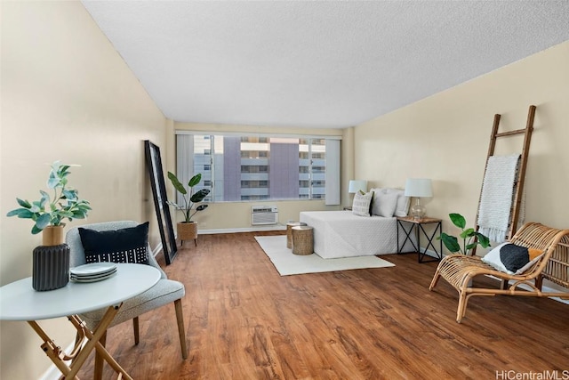 bedroom with hardwood / wood-style flooring, a wall mounted AC, and a textured ceiling