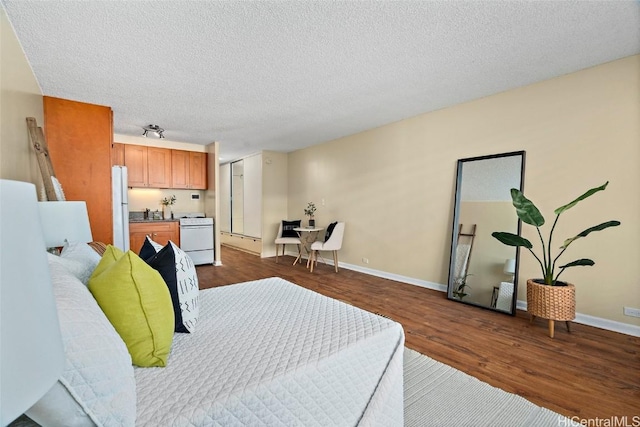 bedroom featuring dark hardwood / wood-style flooring, white fridge, and a textured ceiling